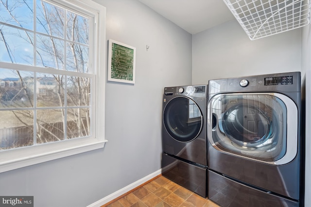 washroom featuring baseboards, separate washer and dryer, and laundry area