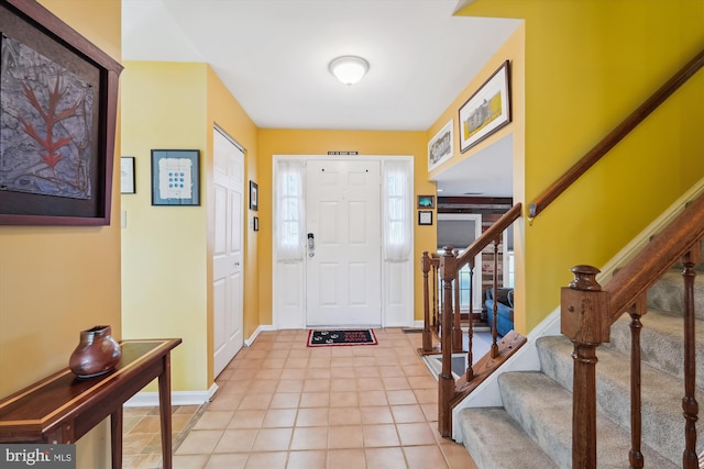 entryway with light tile patterned floors, stairway, and baseboards