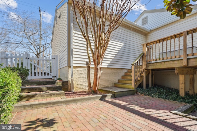 view of side of home with stairway, a patio, and a gate