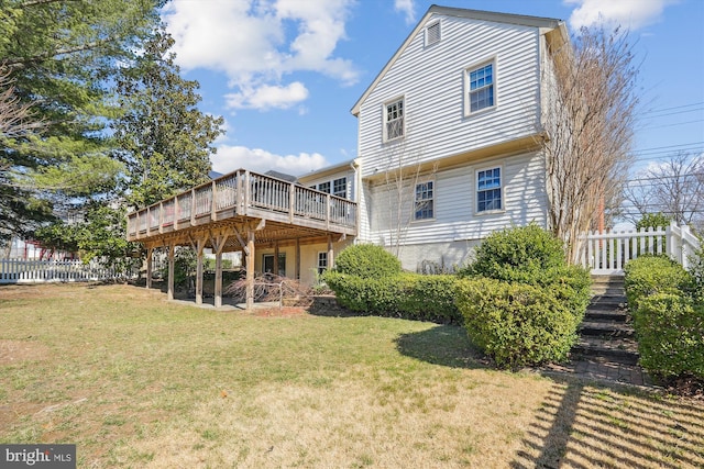 back of property with a lawn, a deck, and fence