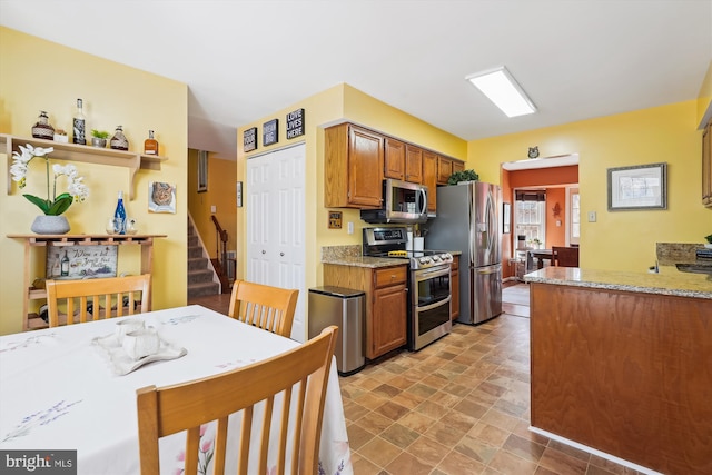 kitchen featuring light stone counters, brown cabinets, and appliances with stainless steel finishes