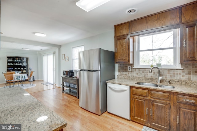 kitchen with visible vents, dishwasher, freestanding refrigerator, light wood-style floors, and a sink