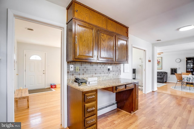 kitchen featuring light wood-type flooring, tasteful backsplash, visible vents, and a baseboard heating unit