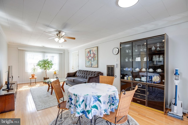 dining space with ornamental molding, a ceiling fan, and wood finished floors