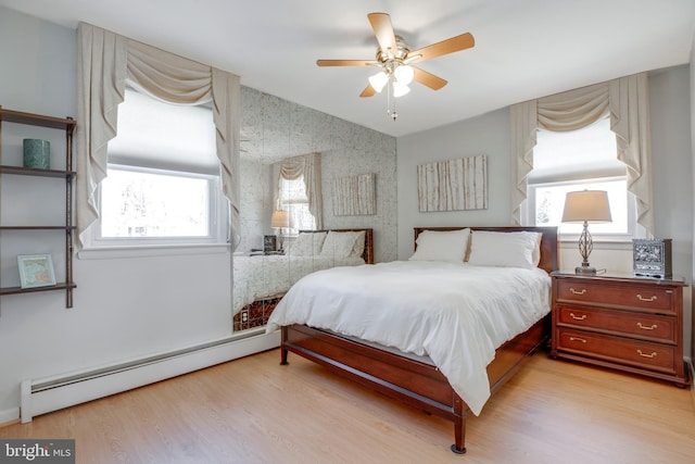 bedroom featuring vaulted ceiling, ceiling fan, baseboard heating, and light wood-style flooring