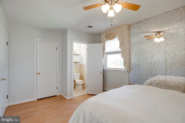 bedroom with a baseboard radiator, visible vents, light wood-style flooring, a ceiling fan, and connected bathroom