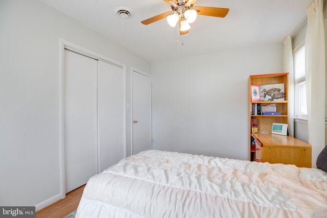 bedroom featuring a ceiling fan, visible vents, and wood finished floors