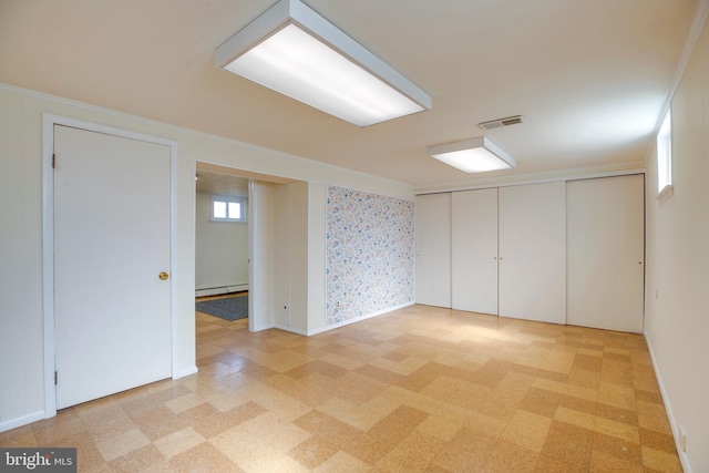 interior space with light floors, visible vents, and baseboard heating