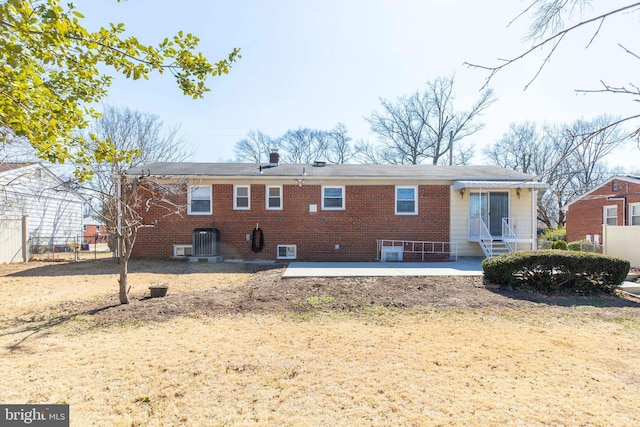 rear view of house featuring brick siding, fence, and a patio