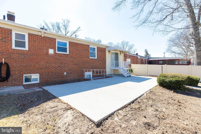 back of house featuring brick siding, a patio area, and fence