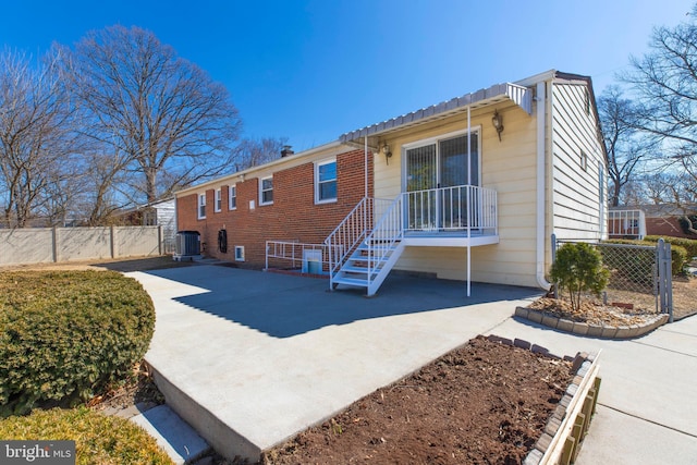 view of front of home featuring central AC unit, fence, metal roof, and brick siding