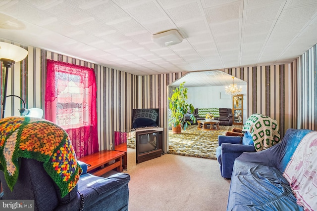 living area with wallpapered walls, a notable chandelier, and carpet floors