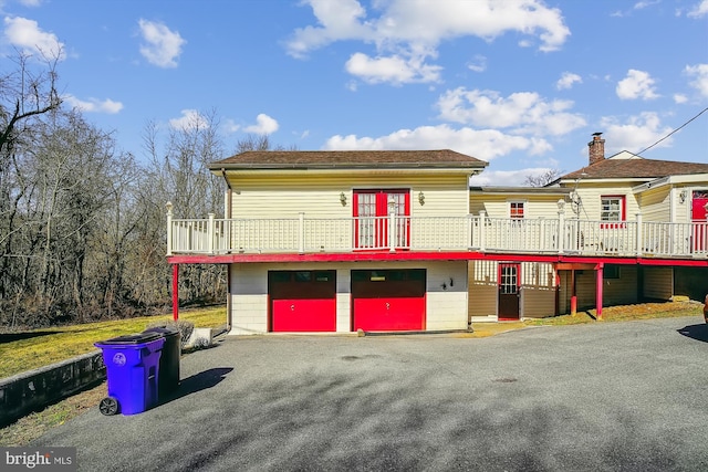 view of front of house featuring a garage, a deck, and driveway