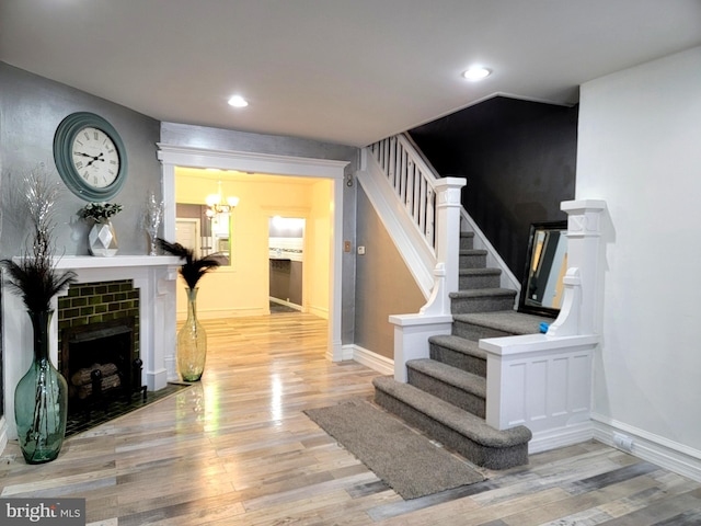 staircase featuring recessed lighting, a fireplace, wood finished floors, and baseboards