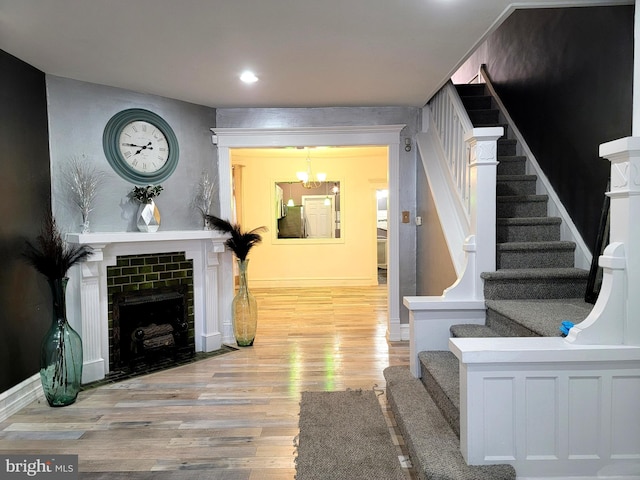 interior space with stairway, a tiled fireplace, wood finished floors, and an inviting chandelier