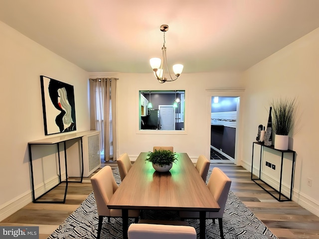 dining area with a chandelier, wood finished floors, and baseboards