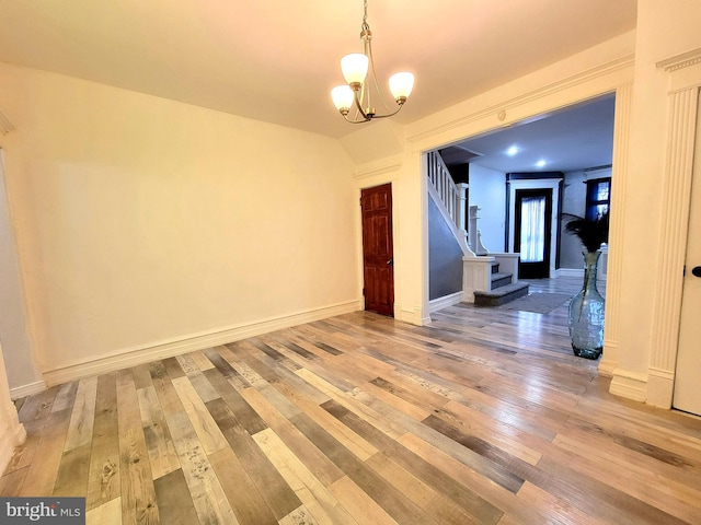 unfurnished room featuring a chandelier, stairway, wood-type flooring, and baseboards