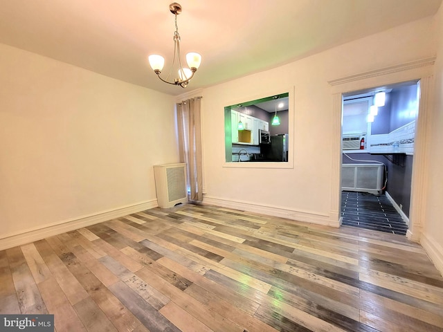 unfurnished dining area with baseboards, a notable chandelier, a sink, and hardwood / wood-style floors