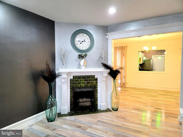 living room featuring a chandelier, a fireplace, wood finished floors, and baseboards