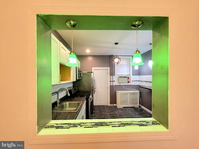 kitchen with appliances with stainless steel finishes, backsplash, a sink, and pendant lighting