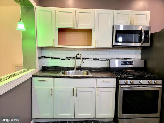 kitchen with dark countertops, backsplash, stainless steel appliances, and a sink