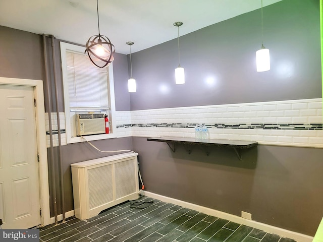 kitchen featuring decorative backsplash, radiator, a breakfast bar area, wood tiled floor, and cooling unit