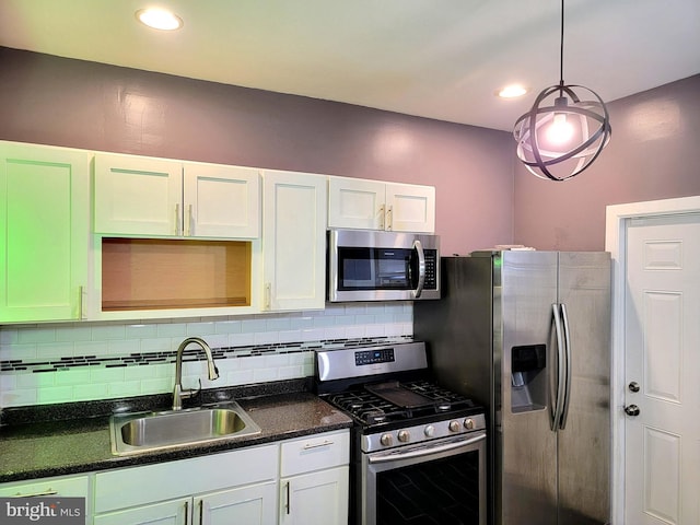 kitchen featuring white cabinets, dark countertops, a sink, stainless steel appliances, and backsplash