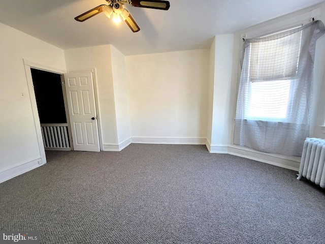 empty room with baseboards, dark colored carpet, ceiling fan, and radiator