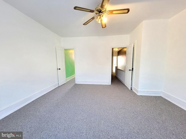 unfurnished bedroom with a ceiling fan, dark colored carpet, and baseboards