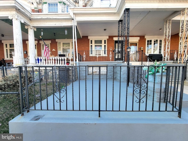 view of front of home with a porch, fence, and brick siding