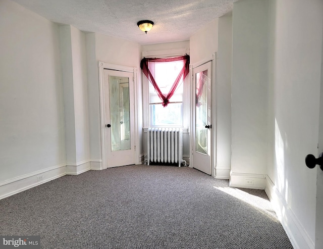 spare room featuring radiator, carpet, and a textured ceiling