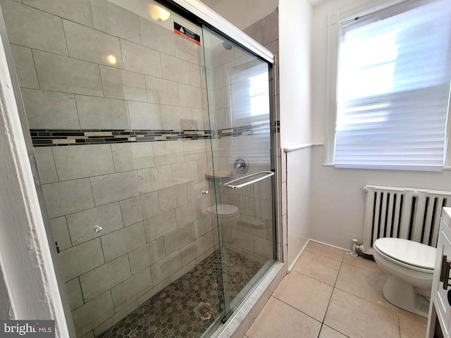 bathroom featuring a healthy amount of sunlight, tile patterned floors, toilet, and radiator