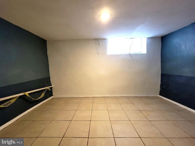 basement featuring light tile patterned floors and baseboards