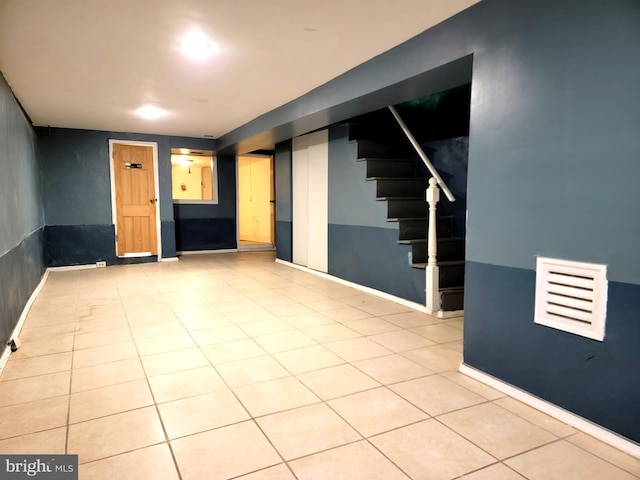 finished below grade area with baseboards, stairway, and tile patterned floors