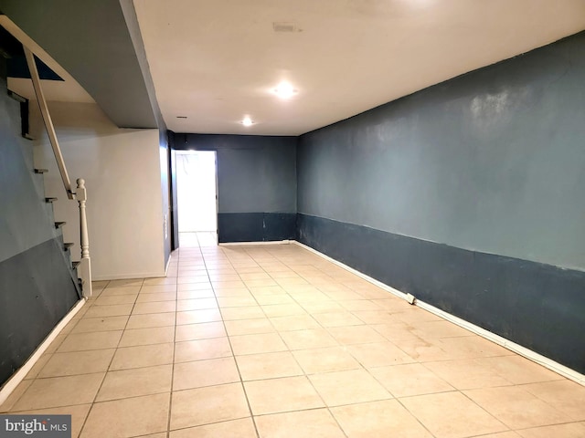 empty room featuring light tile patterned flooring and stairway