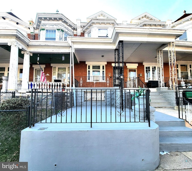 multi unit property with covered porch, fence, and brick siding