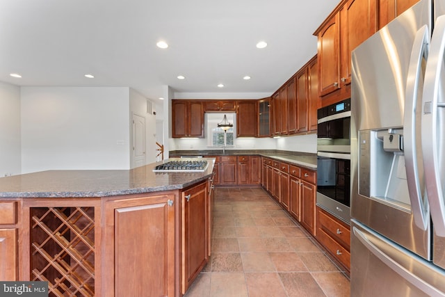 kitchen featuring recessed lighting, appliances with stainless steel finishes, glass insert cabinets, a kitchen island, and dark stone counters