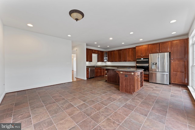 kitchen with baseboards, appliances with stainless steel finishes, a kitchen island, and recessed lighting