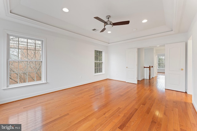 spare room with visible vents, baseboards, light wood-style flooring, a tray ceiling, and recessed lighting