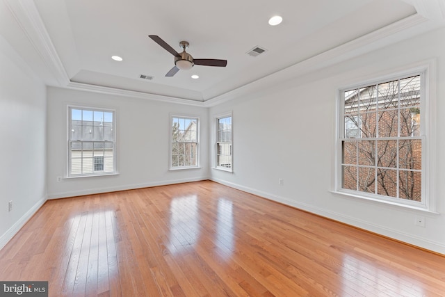 spare room featuring light wood-style floors, visible vents, and a tray ceiling