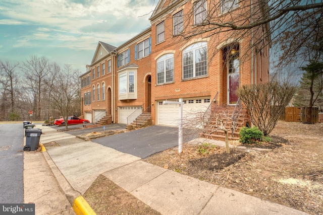 view of property with aphalt driveway, brick siding, and an attached garage