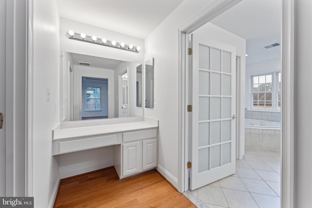 full bath with tiled bath, tile patterned flooring, visible vents, and baseboards