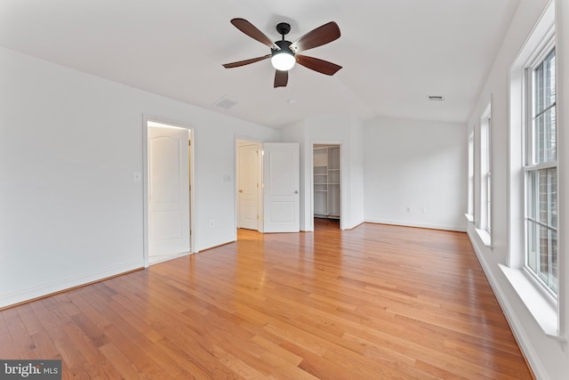 empty room with visible vents, vaulted ceiling, light wood-style flooring, and baseboards