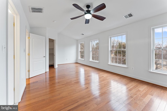 interior space with light wood-style floors, baseboards, visible vents, and vaulted ceiling