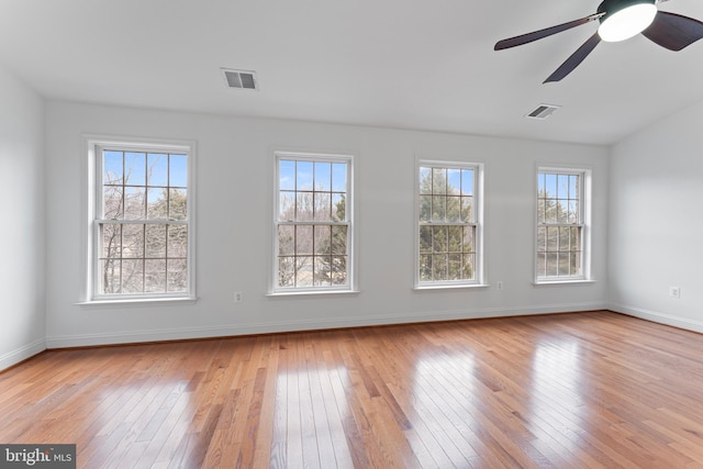 spare room with light wood-type flooring, baseboards, visible vents, and a ceiling fan