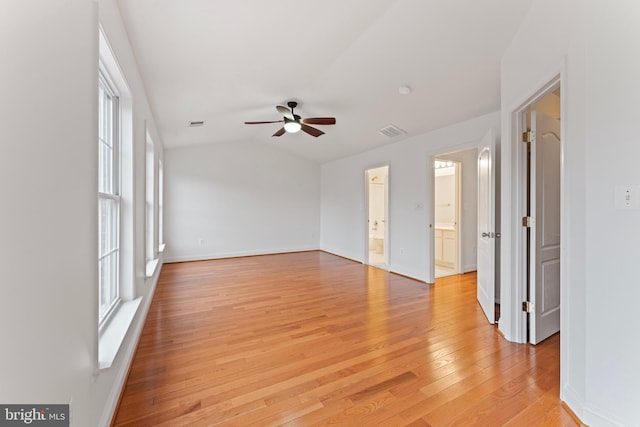 empty room with lofted ceiling, a ceiling fan, visible vents, baseboards, and light wood-type flooring