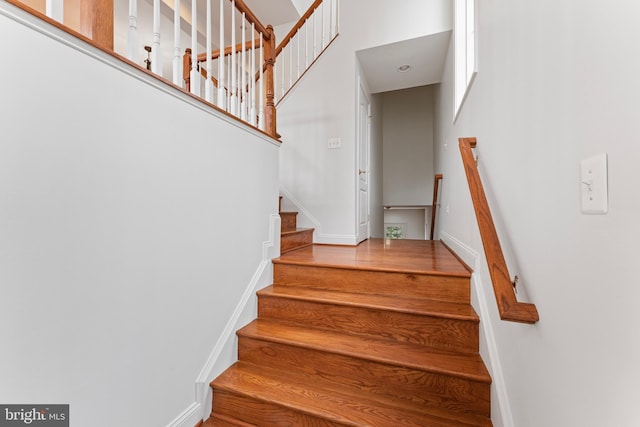 staircase with baseboards and a high ceiling