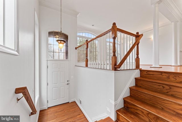 foyer featuring baseboards, stairs, light wood-type flooring, decorative columns, and crown molding