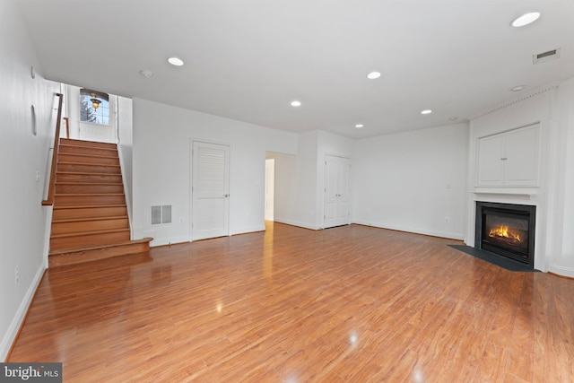 unfurnished living room with light wood finished floors, stairway, and visible vents