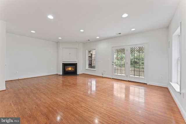 unfurnished living room with light wood-style floors, a fireplace with flush hearth, and recessed lighting